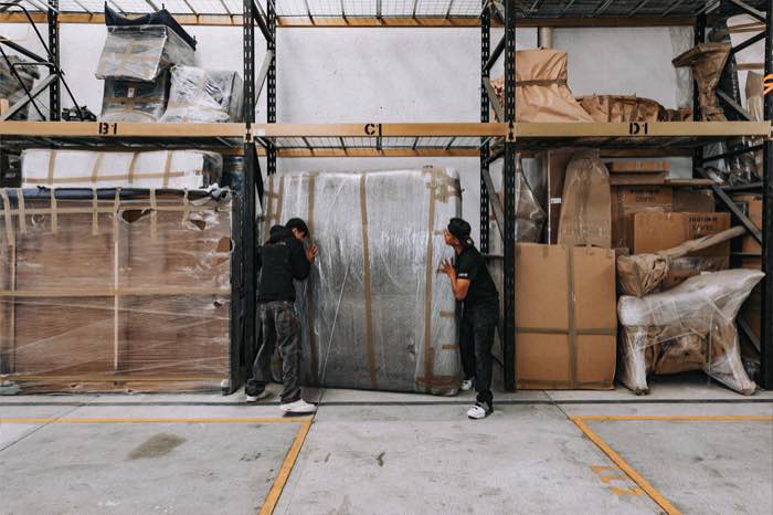 Crew placing a wrapped crate into a racking bay.